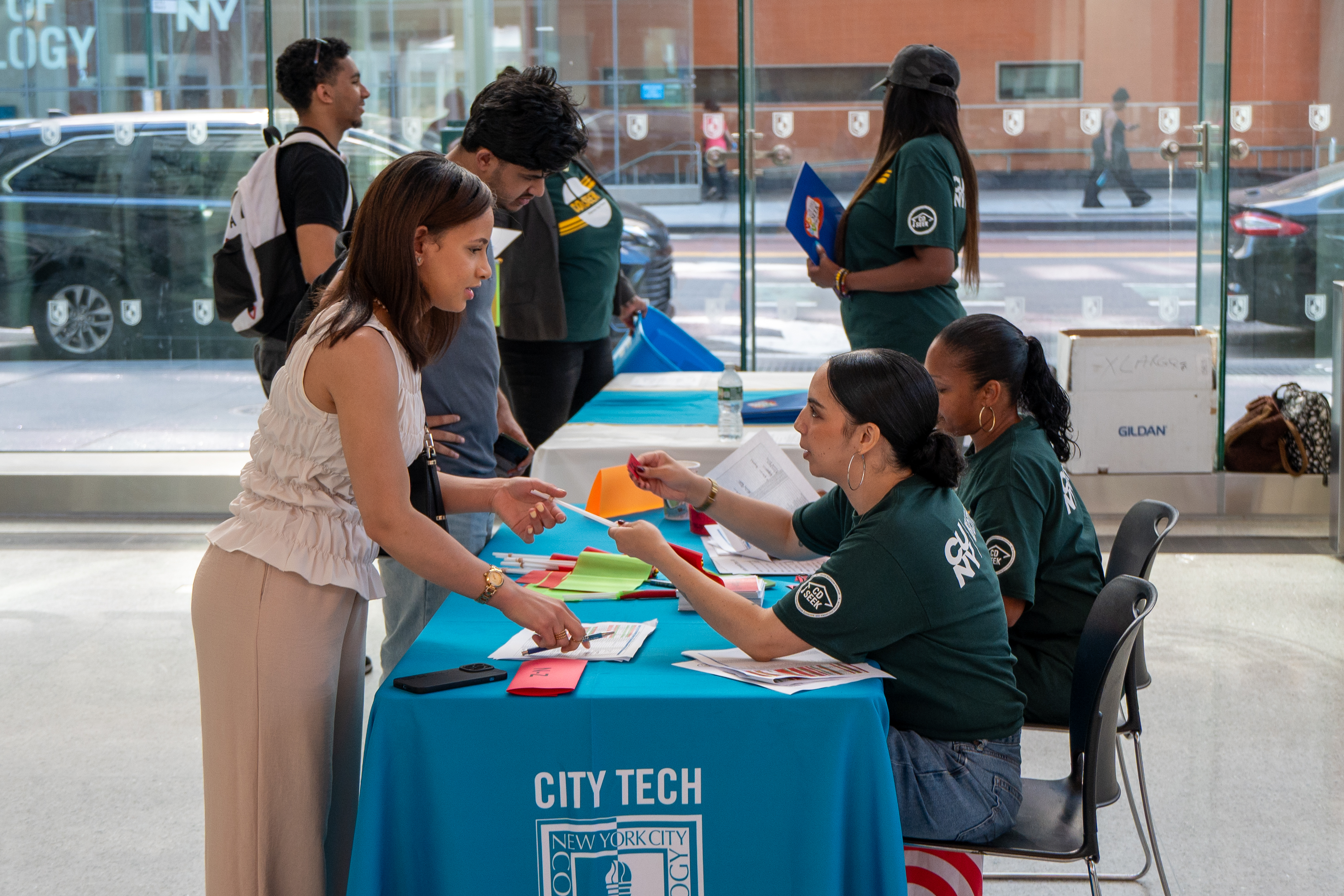 SEEK staff interacting with and checking in students for orientation from the side view of a table.